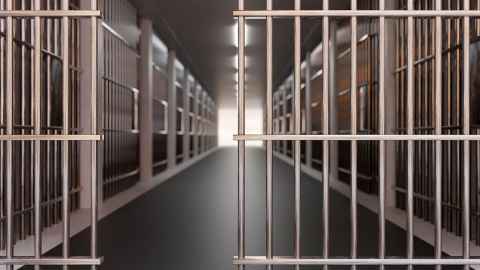 The inside of a prison, with cells covered in bars along a hallway.