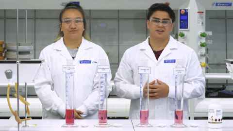 Two people in a lab, wearing white coats.