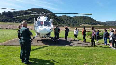 Medical students grouped around a helicopter in a rural area.
