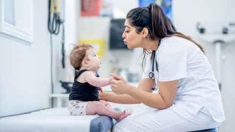 A female doctor interacting with a baby.
