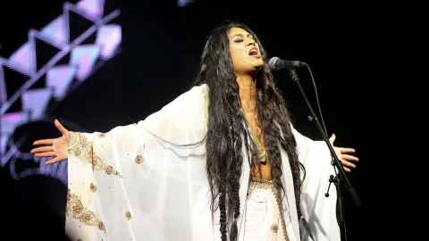 A long-haired woman singing into a microphone.