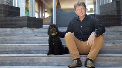 Dr Kyle Eggleton, associate dean rural, and dog Tui sitting on stairs.