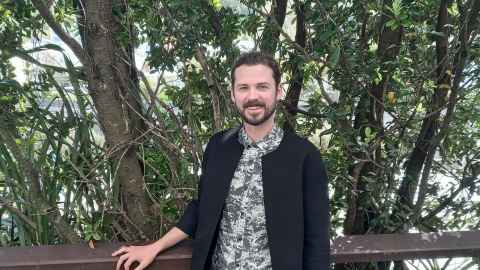 Samuel Andrews stands in front of a tree.