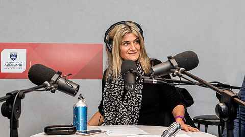 A woman at a microphone, wearing headphones.
