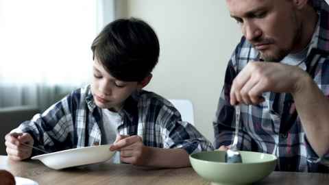 A man and a boy at a table with empty bowls and spoons.