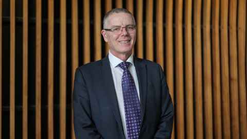 Professor Warwick Bagg against a wooden wall.