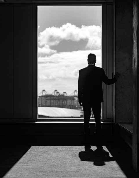 Black and white photo of Professor Robert Greenberg standing at a large window in the new B201 building looking out. Photo: Elise Manahan
