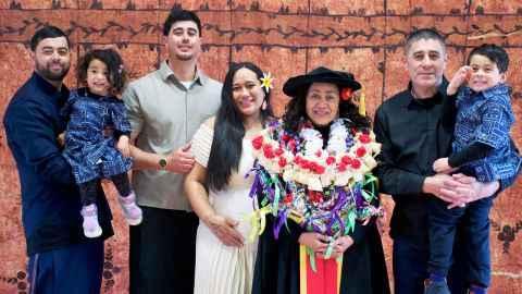 Group photo of Sarah McRobie and her family standing in front of a tapa cloth in the Fale Pasifika.