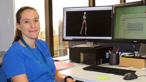 Julie sits in front of a computer with a musculoskeletal image on it