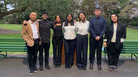 A man and a woman flanking five students in an outdoor setting 