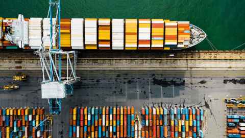Aerial view of industrial port with containers and container ship.