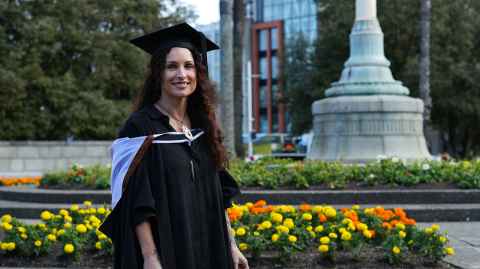 Emily Duncan in front of a garden wearing graduation garb.