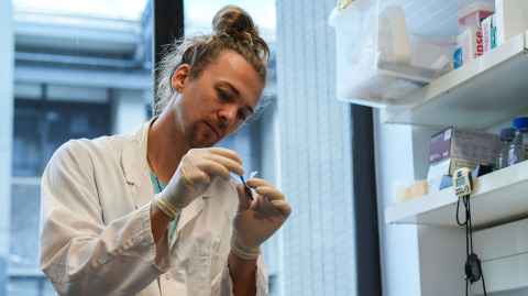 Sam Lasham tests a mushroom in a pipette in a lab.