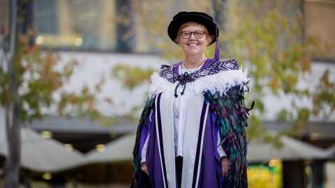 Professor Julia Slark outside the Faculty of Medical and Health Sciences wearing a korowai and her professorial regalia.
