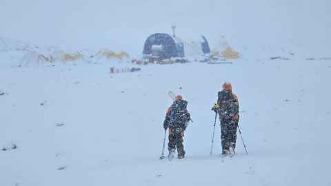 Expedition members returning to camp as a blizzard closes in.
