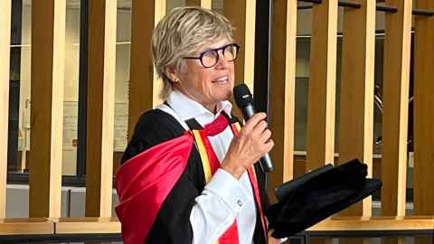 Peg in graduation regalia speaks at the Liggins graduation tea Peg in graduation regalia speaks at the Liggins graduation tea