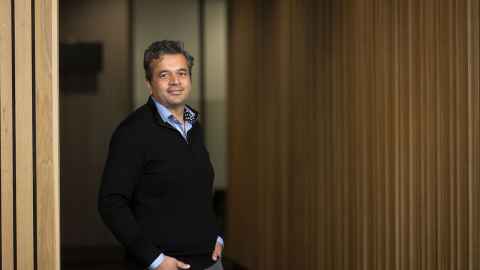 Associate Professor Rohit Ramchandra against a wooden wall.