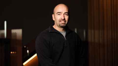 Associate Professor Christopher Hall  against a wooden wall.