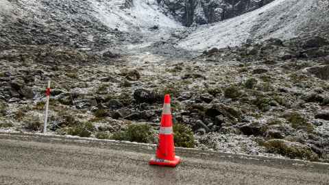 Single orange cones in front of snow-capped mountain 