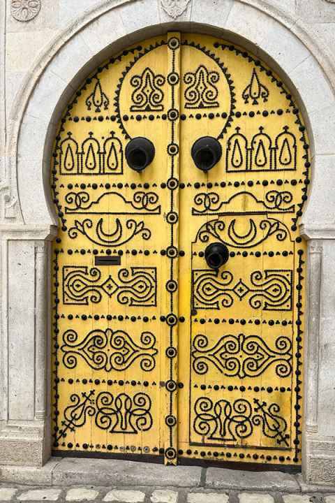 Ornate old yellow and black door in the Arab style in Tunis, Tunisia.