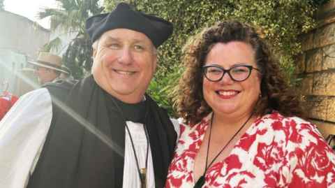 Morag Atchison and Rev Canon Dr John Ashley Null in Tunis, North Africa against a brick and green background.