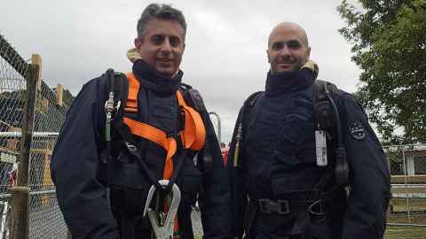 Two men in full firefighter gear pose for a photo.
