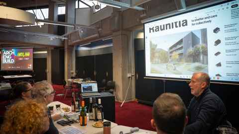 Judges look at a slideshow that shows a housing concept with the word 'Rauhītia'