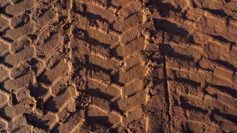 Dark compacted soil with tyre marks. 