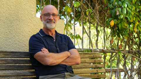 David sits on a bench with a vine behind