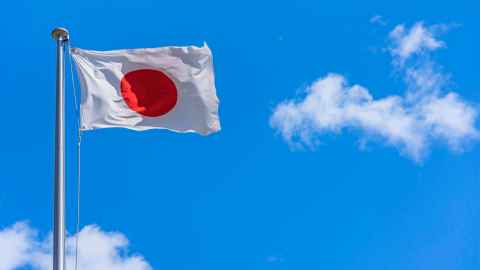 Japanese flag blowing in front of a blue sky
