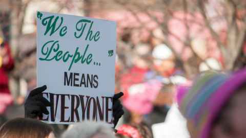 Protestor with "We the people means everyone' sign