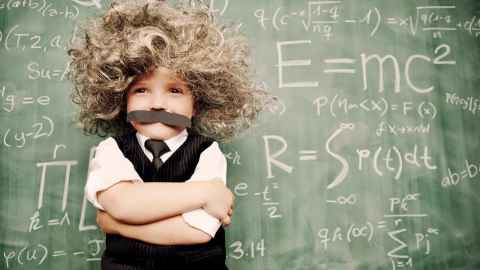 Kids with Einstein-like wig, standing in front of blackboard with maths solutions, including E=MC2