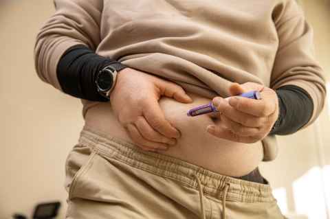 Obese man injects himself in the stomach with a GLP-1 syringe