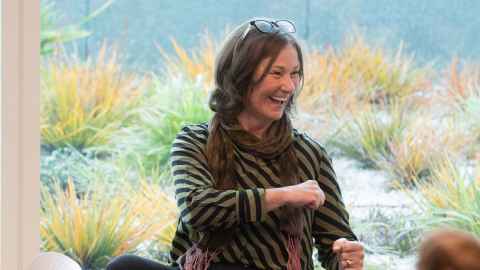 Professor Rebecca Jesson sitting down and laughing during her inaugural lecture on 8 October.
