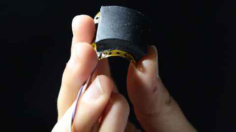 Fingers hold a small rectangular sensor