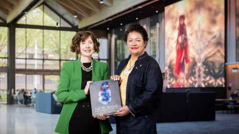Professors Deidre Brown and Ngarino Ellis holding their book Toi Te Mana: An Indigenous History of Māori Art in the atrium of B201, the Arts and Education building. 