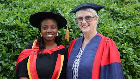 The two of them in regalia in frong of greenery