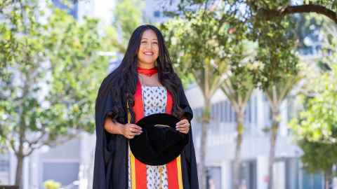 Zanetta Toomata in doctoral garb holding her hat.