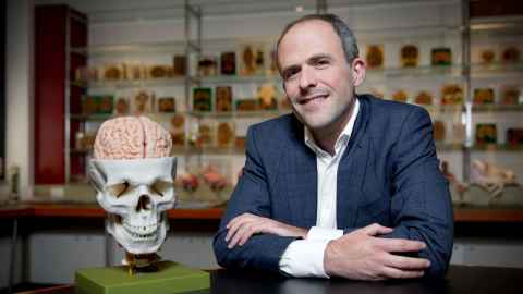 Dr Victor Dieriks beside a model of a skull with brain exposed.