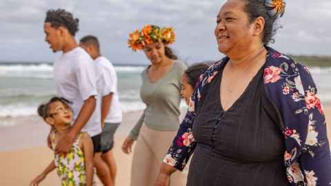 Family of Pacific family walking on beach