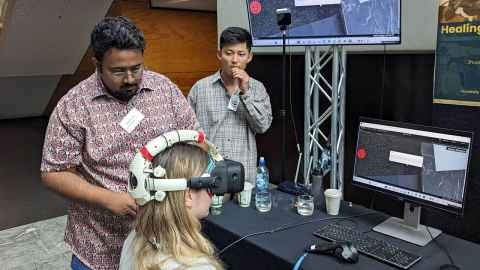 Kunal adjusts a VR headset on a woman