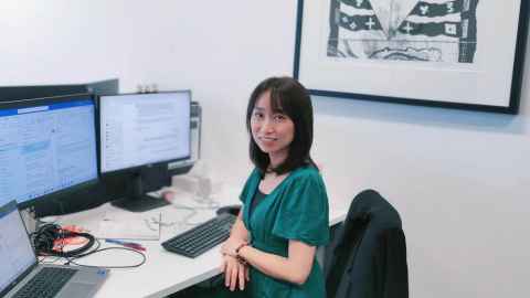 Hui Yee sits at her desk with screens