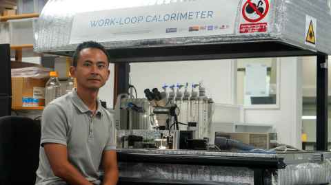 Toan sits in front of an impressive looking machine with headpiece and phials