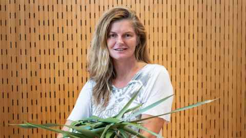 Head and shoulders of Suzette Jackson holding some harakeke