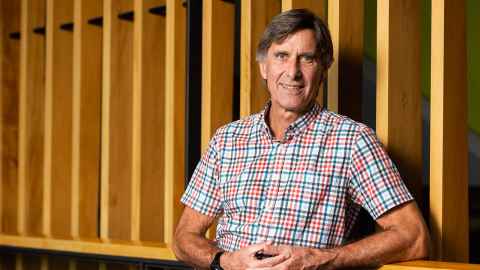 Wayne standing in from of wooden wall at Liggins Institute