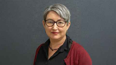 Head and shoulders of Associate Professor Lisa Bailey wearing a black shirt and burgundy cardigan, glasses and a black necklace.
