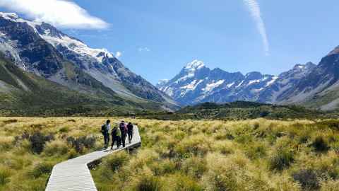 Group of people walking a boardwalk, with Mt Cook in the background. 