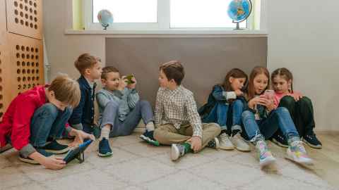 School children floor, all absorbed in technological devices 