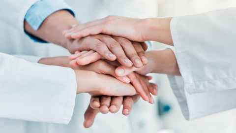 group of scientists hands, one on top of each other, emblem of unity
