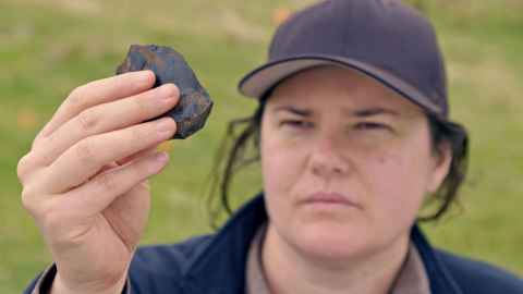Associate Professor Rebecca Phillipps looking at a stone artefact.